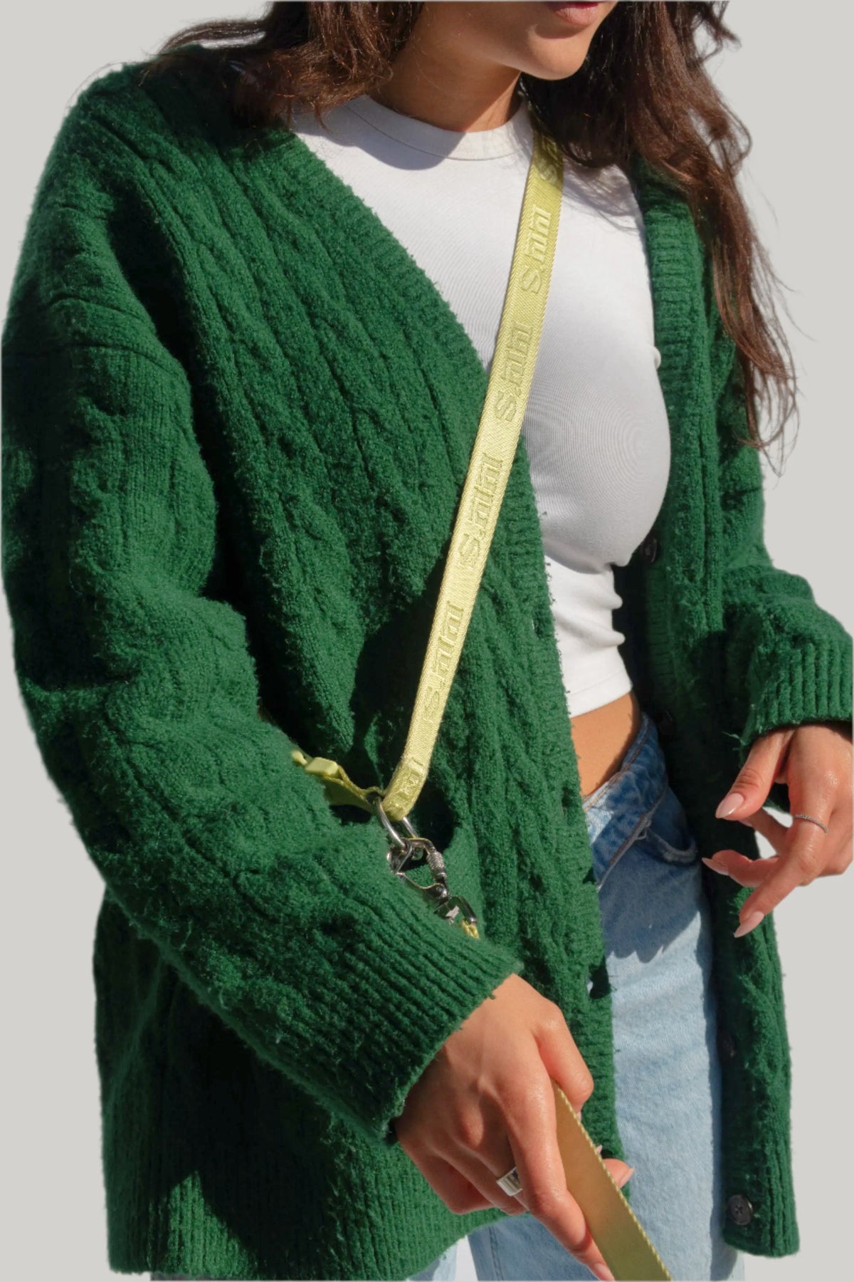 Model wearing green cardigan and white crop top, showcasing Lulu’s from Cali matcha green hands-free dog leash worn crossbody.