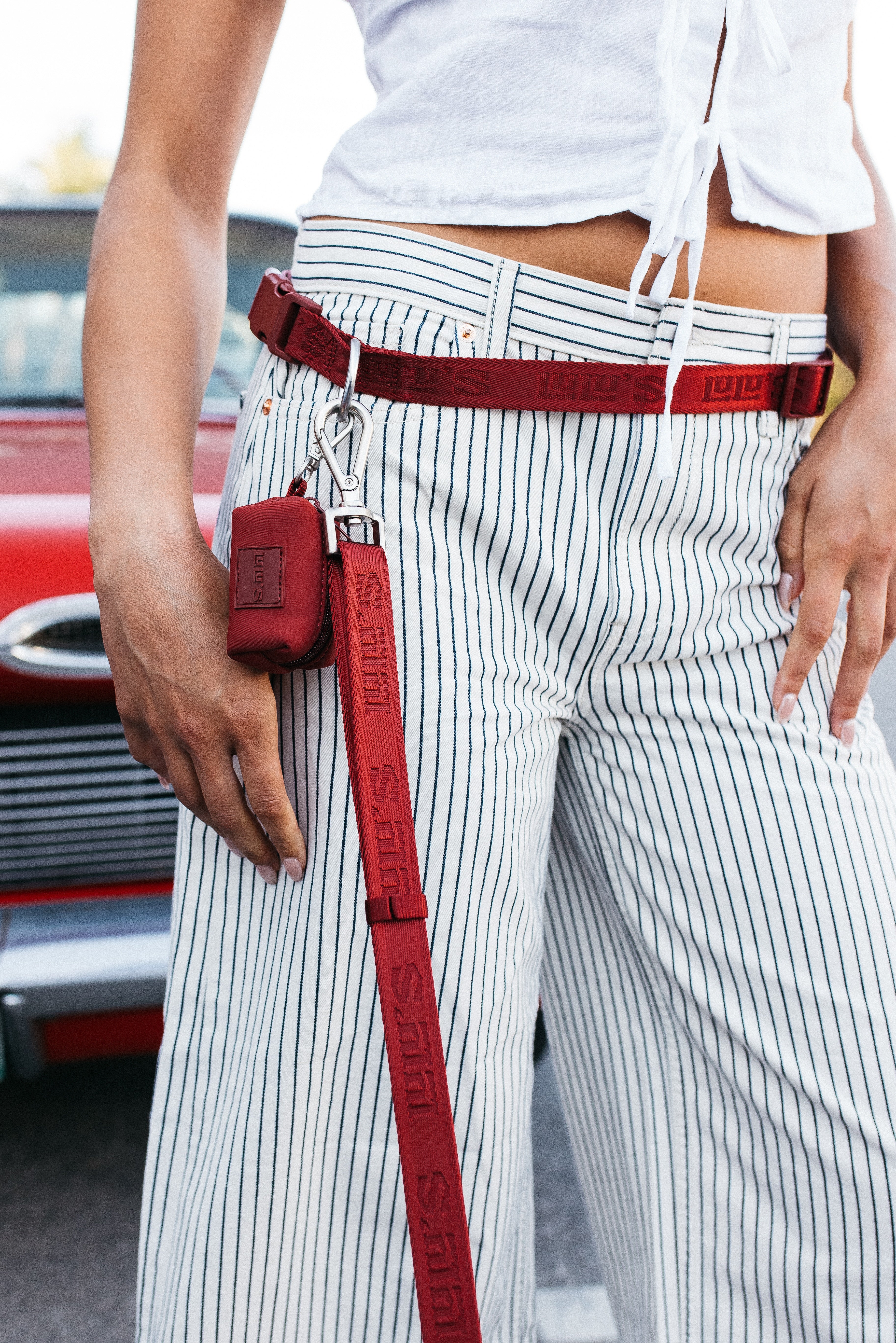 Person wearing a Lulu’s from Cali Cherry Red hands-free dog leash around the waist with matching pouch.