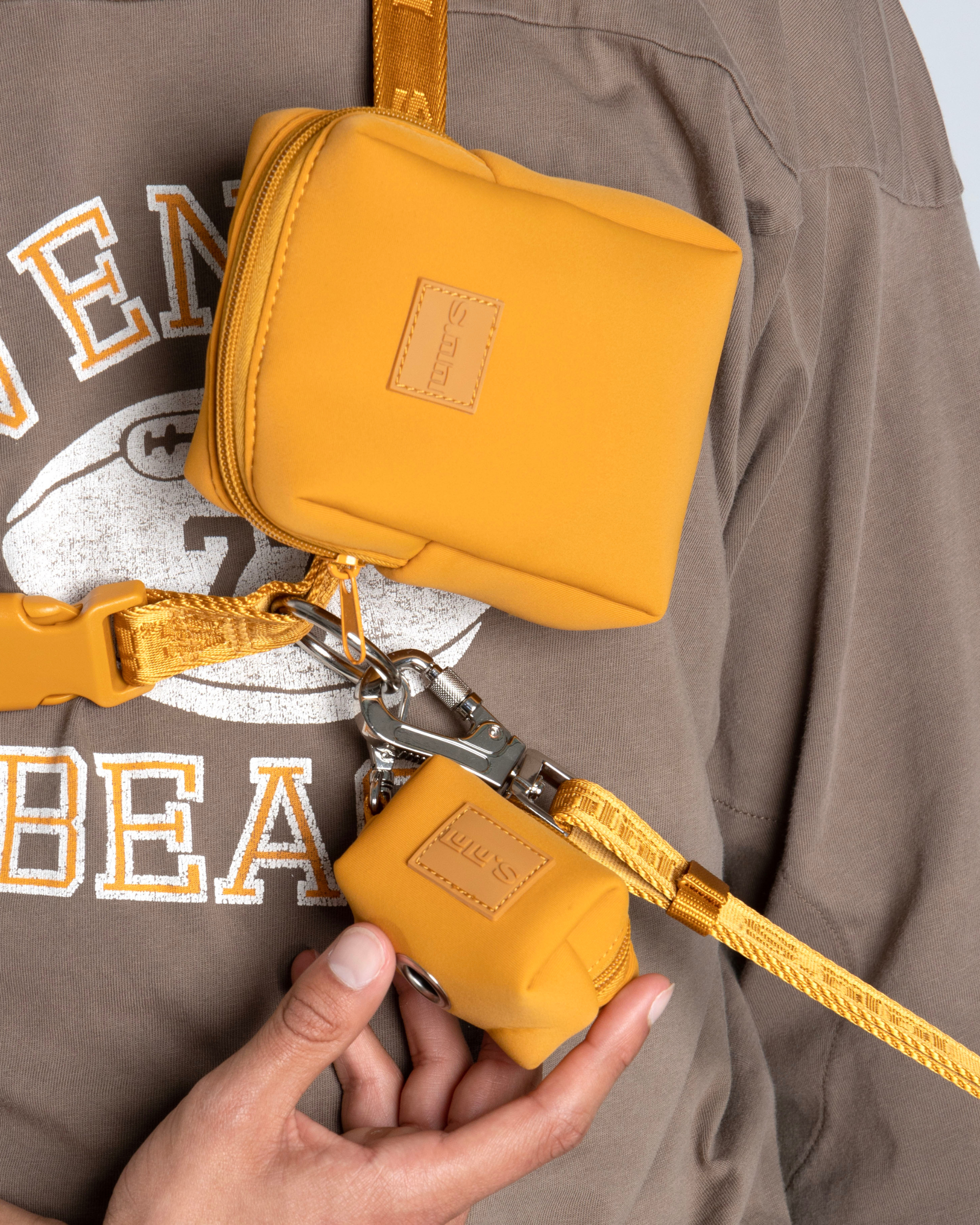 Close-up of a person wearing Lulu's Sunburnt Orange Dog Pouch and holding a matching leash.